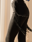 Person wearing black fringed pants with a neutral background