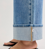 Close-up of blue jeans with a brand label on a light gray background