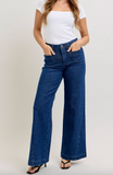 Person wearing blue jeans and a white top on a plain background
