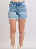 Denim shorts worn by a person on a plain background