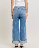 Person wearing light blue wide-leg jeans on a plain background